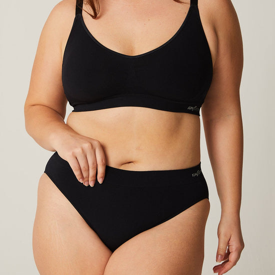 Woman wearing a black bikini set against a plain background