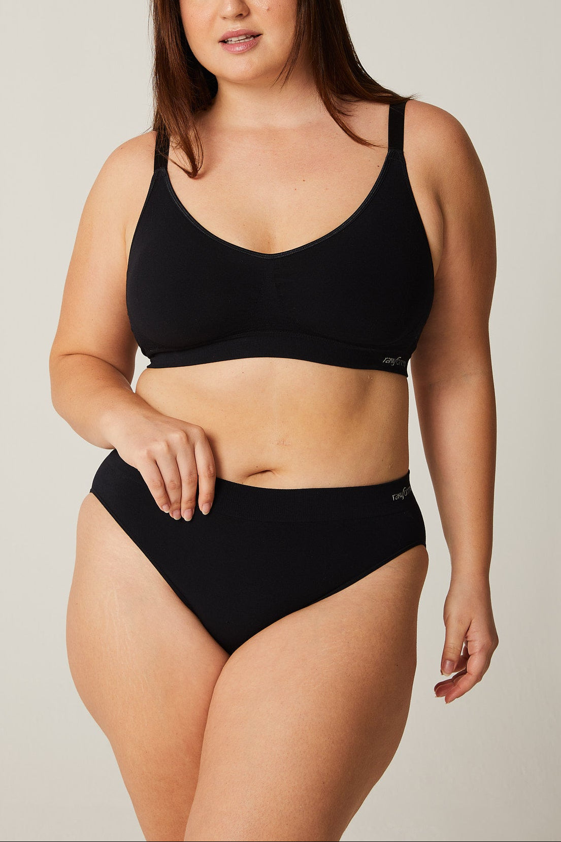 Woman wearing a black bikini set against a plain background