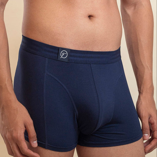 Man wearing navy blue boxer briefs on a beige background