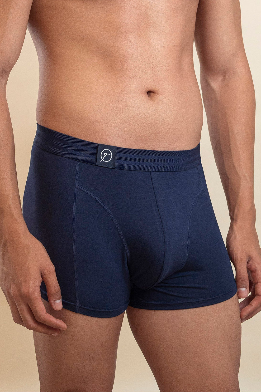 Man wearing navy blue boxer briefs on a beige background