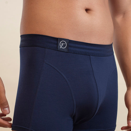 Navy blue boxer briefs worn by a person on a beige background
