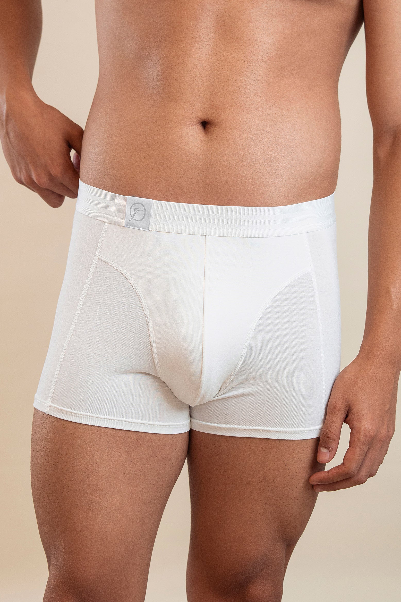 White boxer briefs worn by a person on a beige background