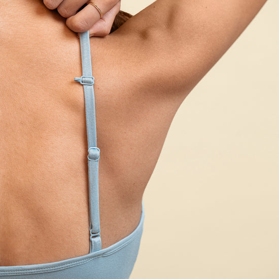 Light blue bra worn by a person on a beige background