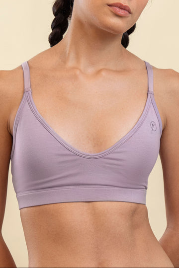Person wearing a light purple sports bra on a beige background