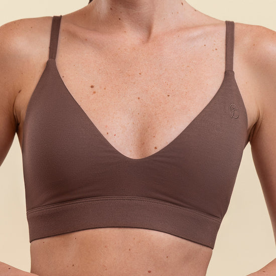 Woman wearing a brown sports bra against a beige background