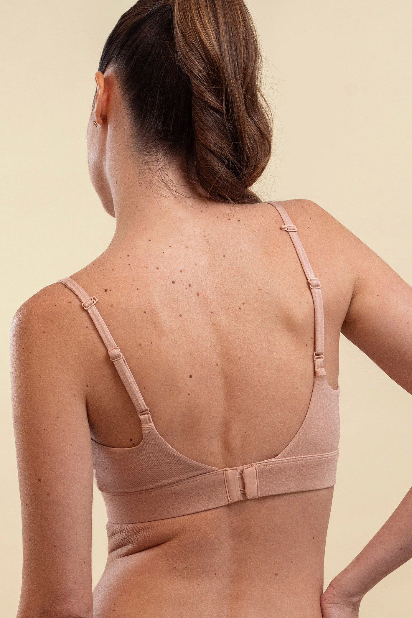 Woman wearing a beige bra against a beige background