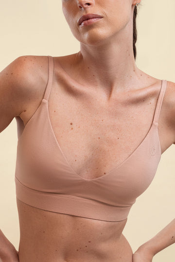 Woman wearing a beige sports bra against a light background