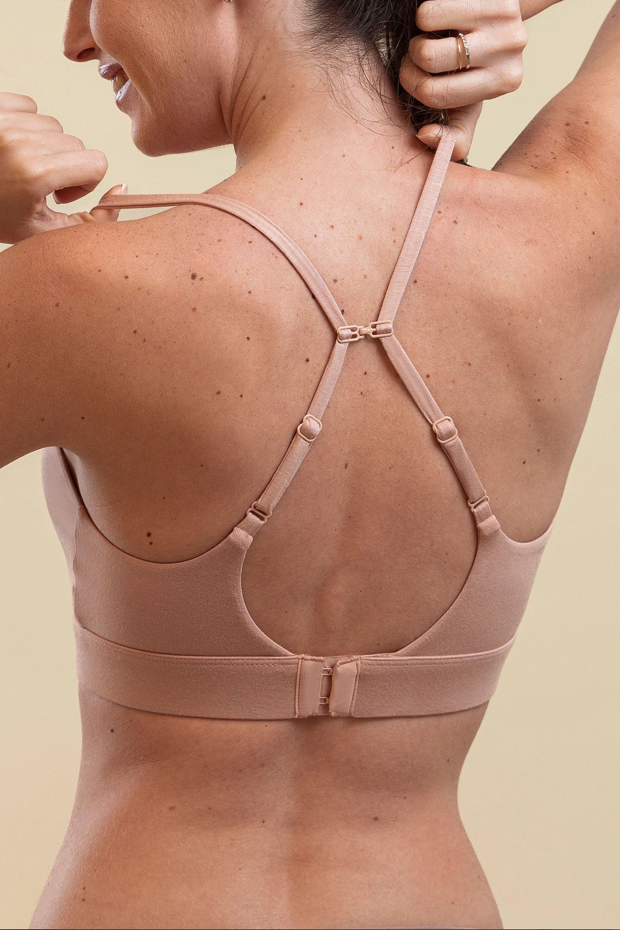 Woman wearing a beige sports bra against a beige background